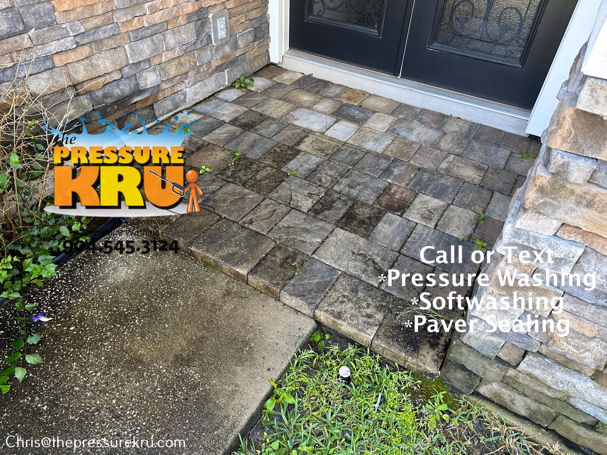 Removing dirt, moss, and weeds from paver driveway before pressure washing in Durbin Crossing.