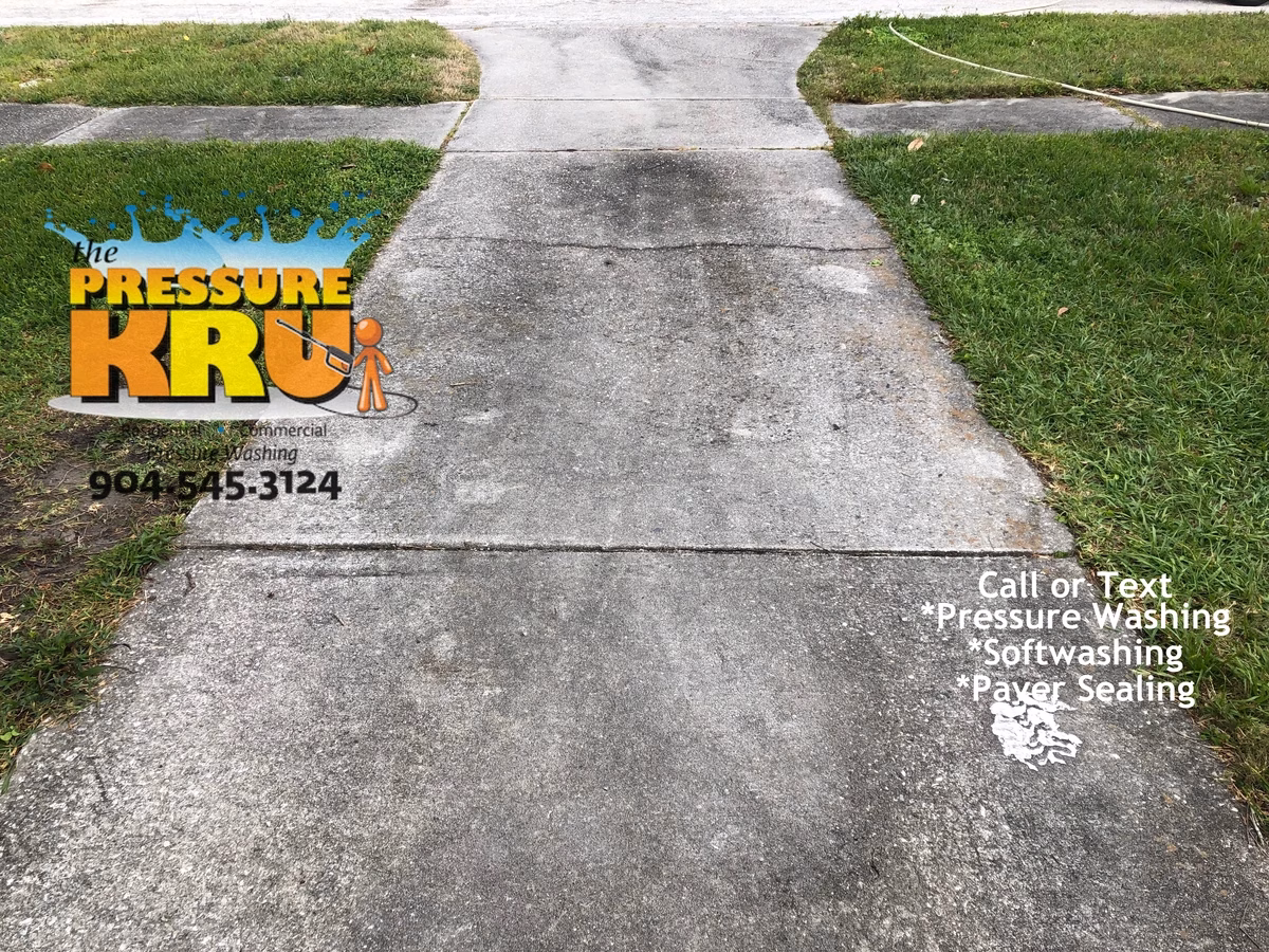 Pressure washing concrete driveway before removing deep set mold and organics in St. Augustine, FL.