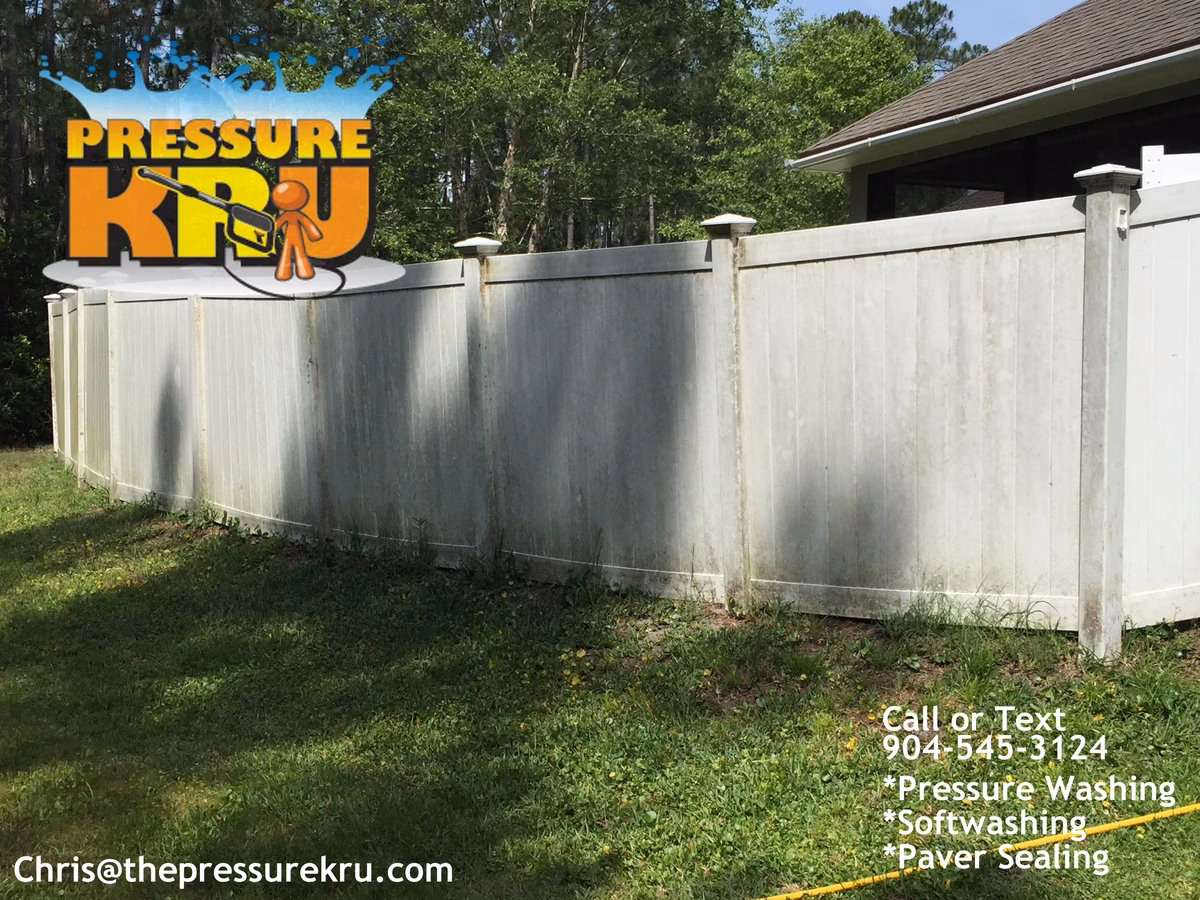 Vinyl fence before low-pressure softwashing in St Johns Golf and Country Club showing green algae stains